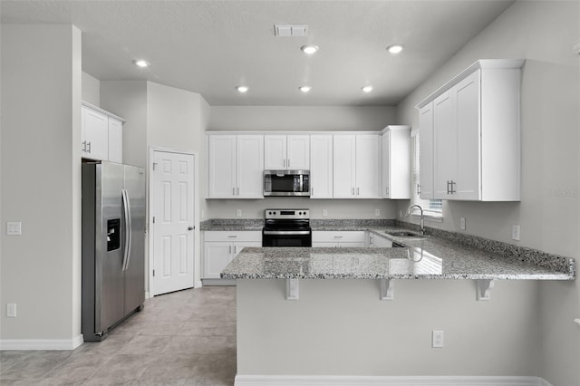 505 Venetian Palms Blvd, New Smyrna Beach, FL 32168 - kitchen featuring appliances with stainless steel finishes, a peninsula, a breakfast bar, light stone counters, and white cabinetry