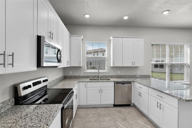 505 Venetian Palms Blvd, New Smyrna Beach, FL 32168 - kitchen with appliances with stainless steel finishes, a peninsula, white cabinetry, a textured ceiling, and recessed lighting