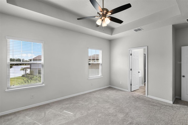 505 Venetian Palms Blvd, New Smyrna Beach, FL 32168 - unfurnished bedroom featuring a tray ceiling, light carpet, and ceiling fan