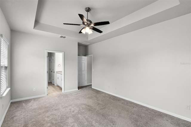 505 Venetian Palms Blvd, New Smyrna Beach, FL 32168 - unfurnished bedroom featuring a raised ceiling, multiple windows, light colored carpet, and ensuite bath