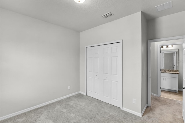 505 Venetian Palms Blvd, New Smyrna Beach, FL 32168 - unfurnished bedroom featuring light carpet, a closet, and a textured ceiling