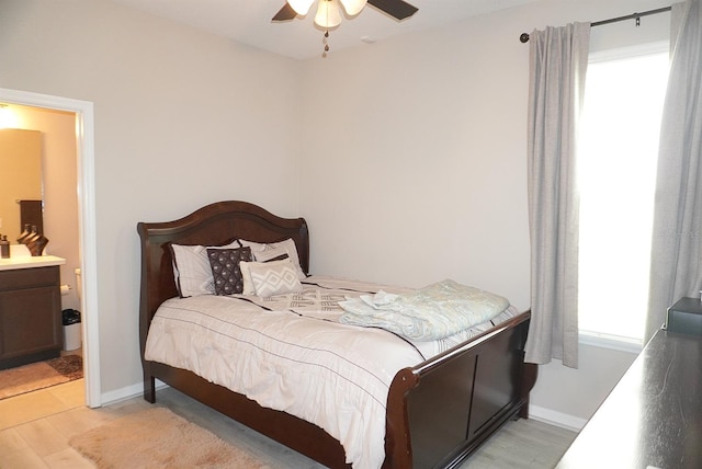 bedroom with light wood-style floors, connected bathroom, and a ceiling fan