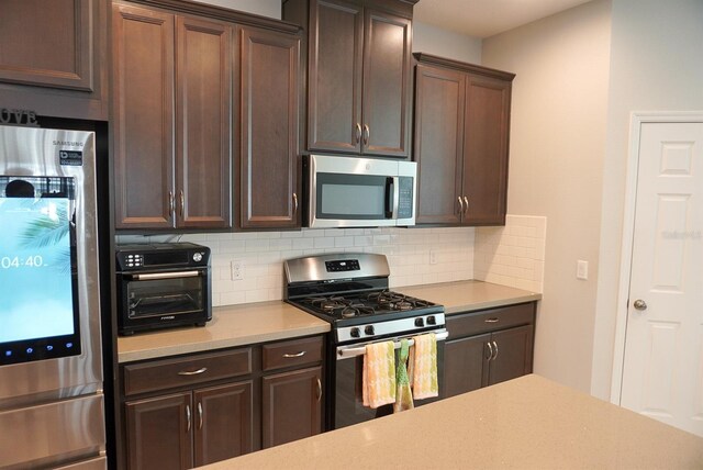 kitchen featuring appliances with stainless steel finishes, decorative backsplash, light countertops, and dark brown cabinetry