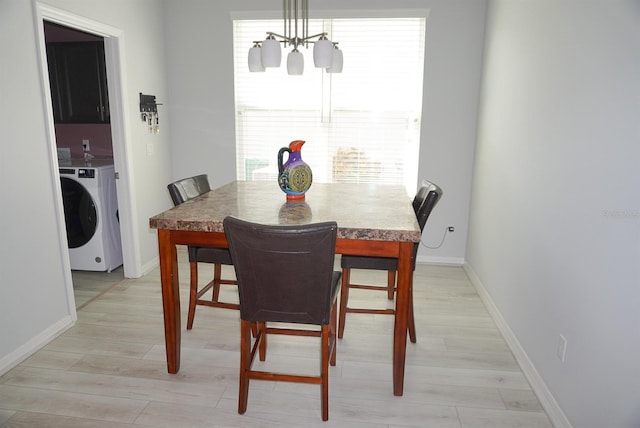 dining area featuring a chandelier, light wood-style floors, and washing machine and clothes dryer