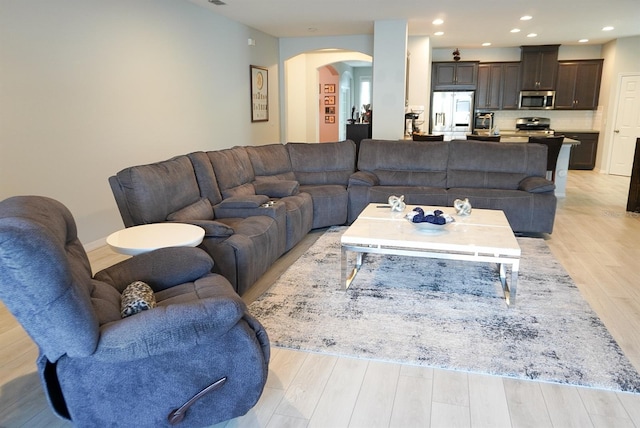 living room featuring arched walkways, light wood-type flooring, and recessed lighting