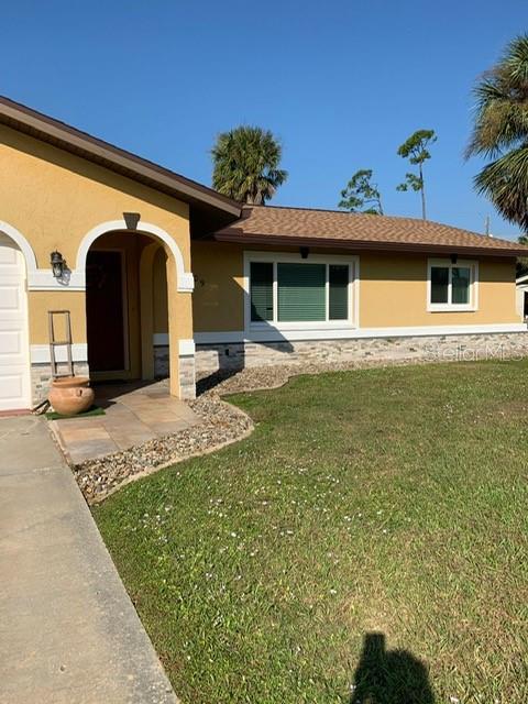 1409 Yorkshire St, Port Charlotte, FL 33952 - view of front of house with stucco siding, a front lawn, and stone siding