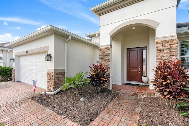 1181 Castlevecchio Loop, Orlando, FL 32825 - entrance to property featuring stone siding, stucco siding, an attached garage, and decorative driveway
