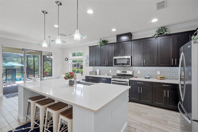100 Verde Way, Debary, FL 32713 - kitchen with stainless steel appliances, ornamental molding, light countertops, a center island with sink, and decorative backsplash