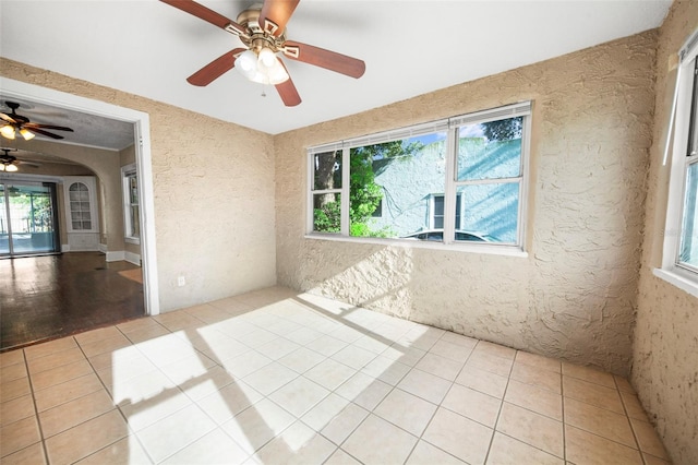 1215 6th St, Clermont, FL 34711 - empty room featuring light tile patterned floors, a ceiling fan, a textured wall, and arched walkways