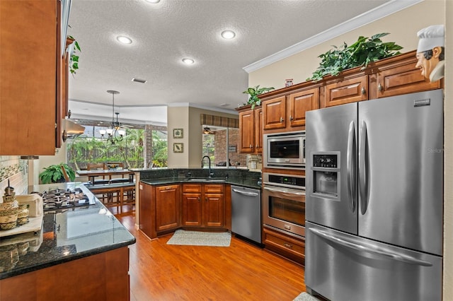 11613 Swift Water Cir, Orlando, FL 32817 - kitchen featuring appliances with stainless steel finishes, crown molding, a peninsula, a textured ceiling, and light wood-style flooring