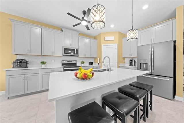 2412 Camden Park Ave, Davenport, FL 33837 - kitchen with stainless steel appliances, a kitchen bar, tasteful backsplash, hanging light fixtures, and a center island with sink
