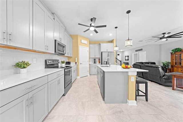 2412 Camden Park Ave, Davenport, FL 33837 - kitchen with appliances with stainless steel finishes, a ceiling fan, decorative backsplash, open floor plan, and light countertops