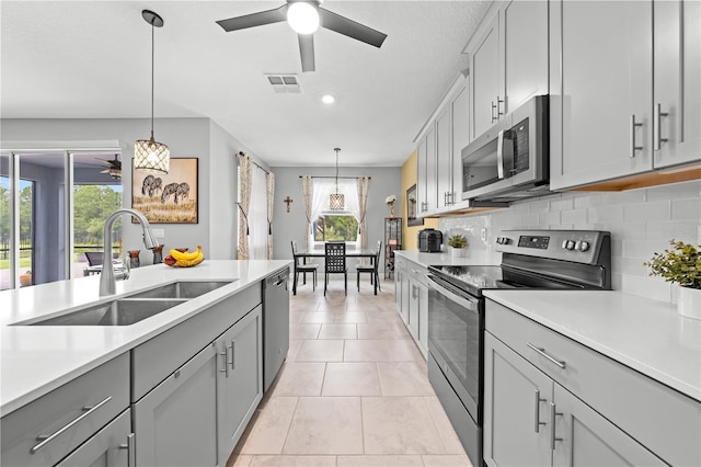 2412 Camden Park Ave, Davenport, FL 33837 - kitchen with stainless steel appliances, ceiling fan, gray cabinetry, and healthy amount of natural light