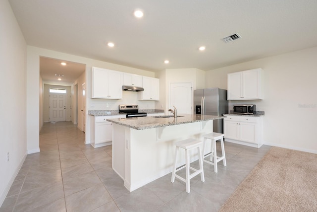 3241 Silas Dr, New Smyrna Beach, FL 32168 - kitchen with appliances with stainless steel finishes, a kitchen breakfast bar, light stone counters, an island with sink, and white cabinetry