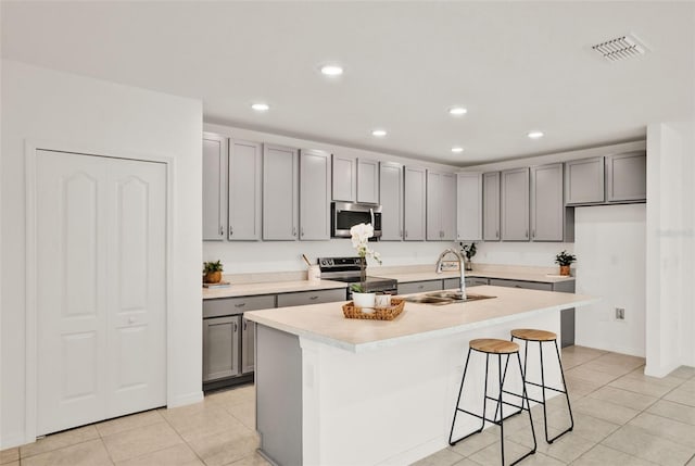 554 Pawnee Ct, Haines City, FL 33844 - kitchen featuring appliances with stainless steel finishes, gray cabinetry, light tile patterned floors, an island with sink, and recessed lighting