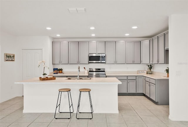 554 Pawnee Ct, Haines City, FL 33844 - kitchen with appliances with stainless steel finishes, gray cabinets, a center island with sink, recessed lighting, and light tile patterned floors