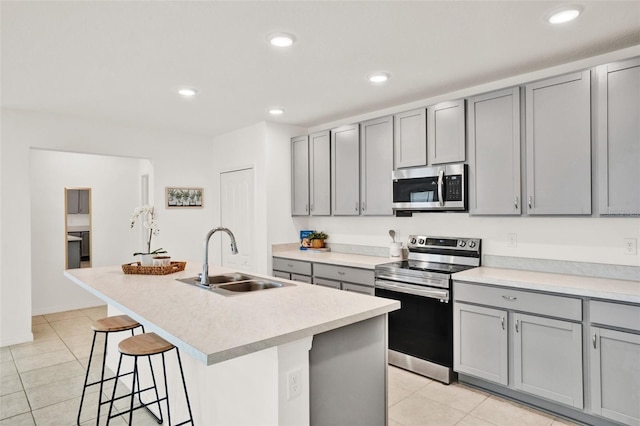 554 Pawnee Ct, Haines City, FL 33844 - kitchen with stainless steel appliances, gray cabinetry, light tile patterned floors, a breakfast bar, and a center island with sink