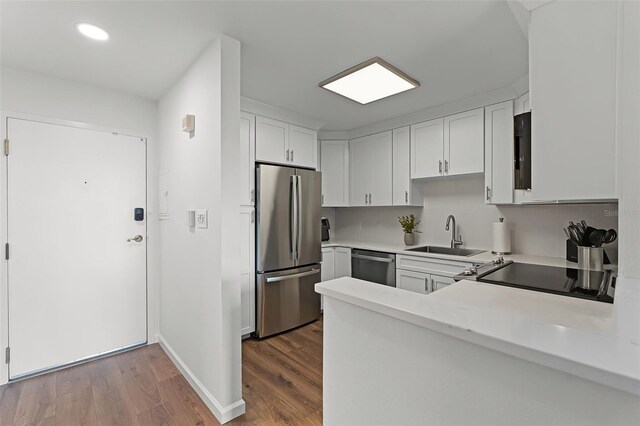 1100 Delaney Ave Unit F407, Orlando, FL 32806 - kitchen featuring stainless steel appliances, wood finished floors, light countertops, white cabinets, and a peninsula