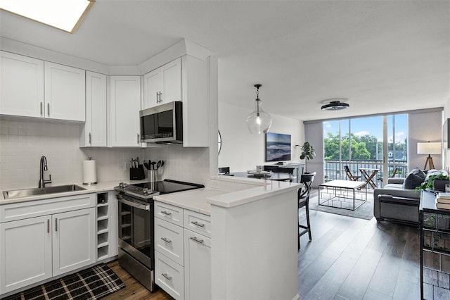 1100 Delaney Ave Unit F407, Orlando, FL 32806 - kitchen with stainless steel appliances, tasteful backsplash, a peninsula, floor to ceiling windows, and dark wood finished floors