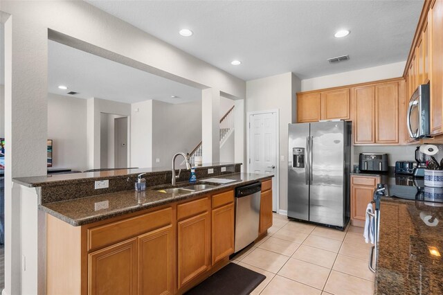 594 Hernando Pl, Clermont, FL 34715 - kitchen with stainless steel appliances, dark stone countertops, light tile patterned flooring, recessed lighting, and brown cabinetry