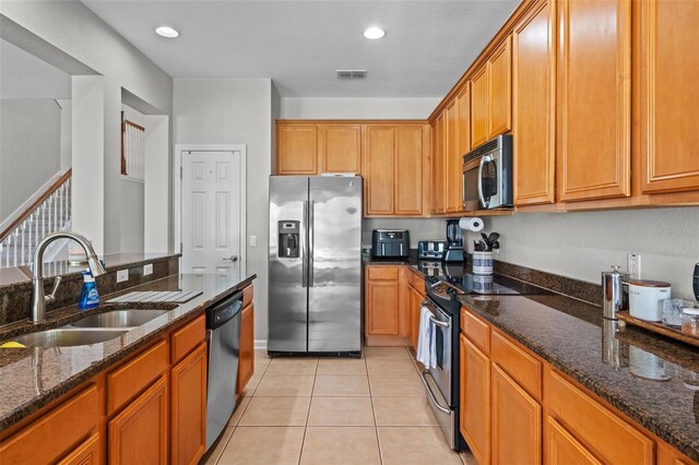 594 Hernando Pl, Clermont, FL 34715 - kitchen with appliances with stainless steel finishes, light tile patterned floors, dark stone counters, brown cabinets, and recessed lighting