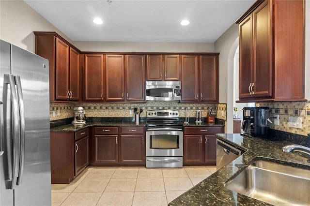 2122 Bent Grass Ave, Ocoee, FL 34761 - kitchen with stainless steel appliances, dark stone countertops, backsplash, light tile patterned floors, and dark brown cabinets