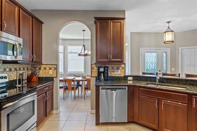 2122 Bent Grass Ave, Ocoee, FL 34761 - kitchen featuring stainless steel appliances, dark stone counters, backsplash, and decorative light fixtures