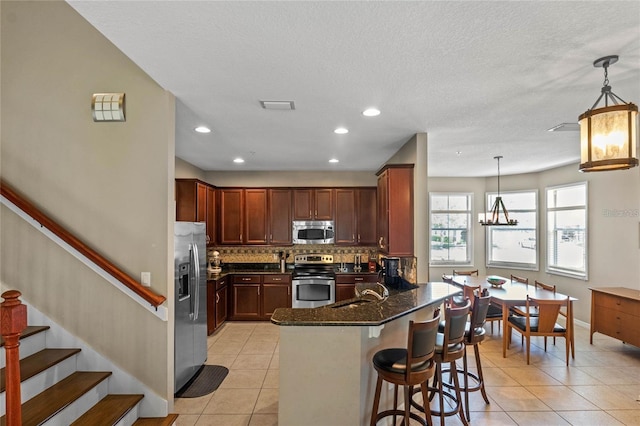 2122 Bent Grass Ave, Ocoee, FL 34761 - kitchen with appliances with stainless steel finishes, light tile patterned flooring, decorative backsplash, a peninsula, and recessed lighting