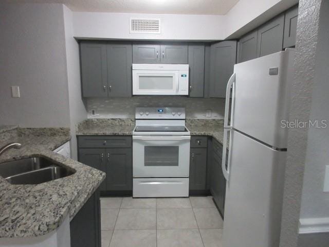 831 Camargo Way Unit 106, Altamonte Springs, FL 32714 - kitchen with white appliances, light tile patterned flooring, gray cabinets, and light stone counters