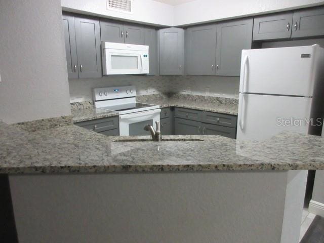 831 Camargo Way Unit 106, Altamonte Springs, FL 32714 - kitchen with white appliances, gray cabinetry, light stone counters, and a peninsula