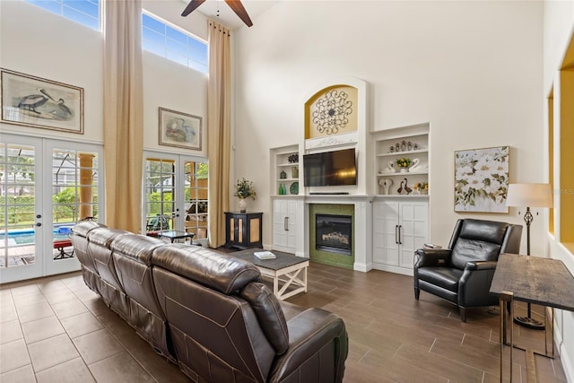 8424 Lake Burden Cir, Windermere, FL 34786 - living area with french doors, a towering ceiling, ceiling fan, healthy amount of natural light, and a glass covered fireplace