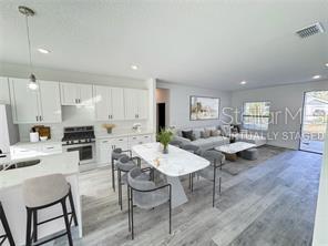 572 W Bluster Pl, Citrus Springs, FL 34434 - kitchen with range, white cabinetry, light wood-type flooring, light countertops, and recessed lighting
