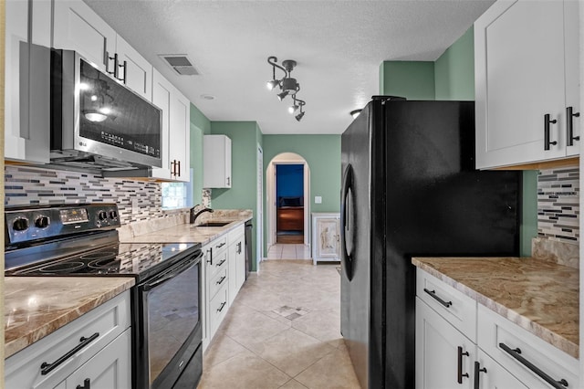 851 Bates Ct, Casselberry, FL 32707 - kitchen with black electric range oven, stainless steel microwave, freestanding refrigerator, backsplash, and arched walkways