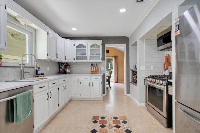 1035 Paladin Ct, Orlando, FL 32812 - kitchen with appliances with stainless steel finishes, decorative backsplash, ornamental molding, light countertops, and white cabinetry