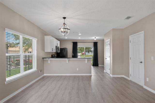1030 Bending Oak Trl, Winter Garden, FL 34787 - kitchen with freestanding refrigerator, light wood-style flooring, a chandelier, white cabinets, and stainless steel microwave