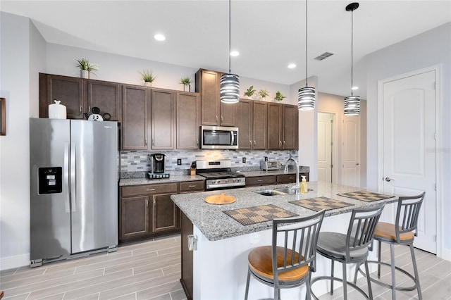 2302 Datura Loop, Saint Cloud, FL 34772 - kitchen with appliances with stainless steel finishes, decorative backsplash, an island with sink, dark brown cabinetry, and recessed lighting