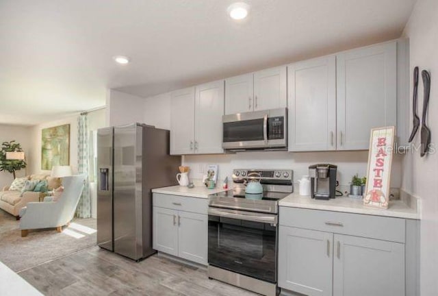 21 Locust Ter, Ocala, FL 34472 - kitchen with appliances with stainless steel finishes, light countertops, light wood-style floors, open floor plan, and gray cabinetry