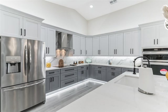 18623 Tunbridge St, Orlando, FL 32833 - kitchen with appliances with stainless steel finishes, wall chimney range hood, gray cabinetry, decorative backsplash, and lofted ceiling