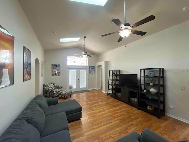 8071 Roaring Creek Ct, Kissimmee, FL 34747 - living room with arched walkways, lofted ceiling, ceiling fan, a skylight, and light wood-style floors