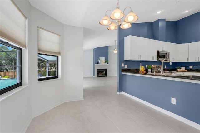 1173 Trotwood Blvd, Winter Springs, FL 32708 - kitchen featuring dark countertops, stainless steel microwave, a chandelier, white cabinetry, and pendant lighting
