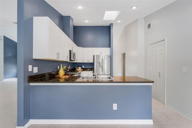 1173 Trotwood Blvd, Winter Springs, FL 32708 - kitchen with appliances with stainless steel finishes, a peninsula, white cabinets, a towering ceiling, and light tile patterned flooring