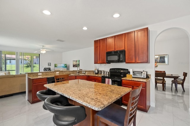 2982 Camino Real Dr S, Kissimmee, FL 34744 - kitchen featuring black appliances, light marble finish flooring, a peninsula, a kitchen bar, and recessed lighting