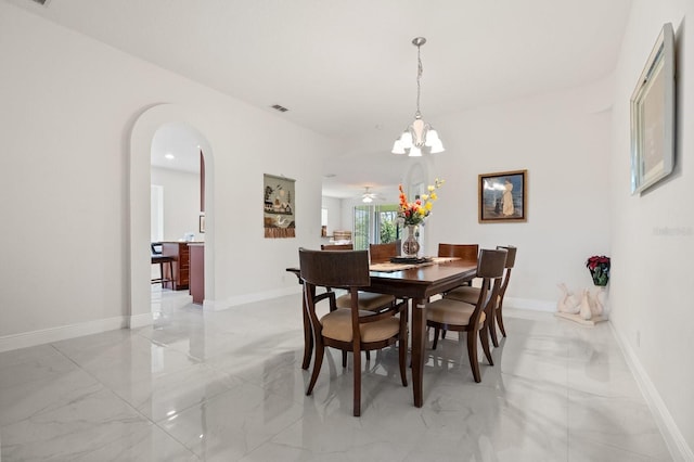 2982 Camino Real Dr S, Kissimmee, FL 34744 - dining space with arched walkways, light marble finish floors, and a chandelier