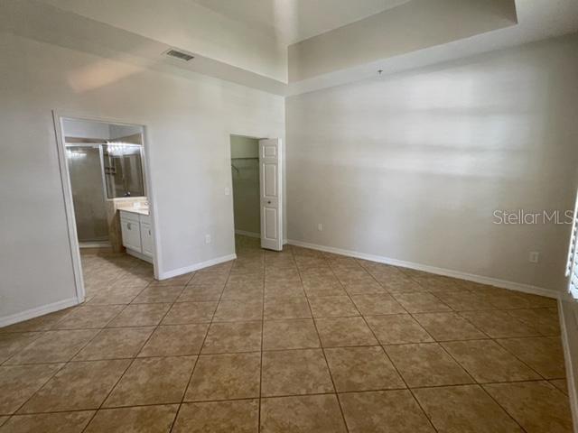 949 Westpark Dr Unit 107, Celebration, FL 34747 - unfurnished bedroom with tile patterned flooring, a walk in closet, ensuite bath, a towering ceiling, and a closet