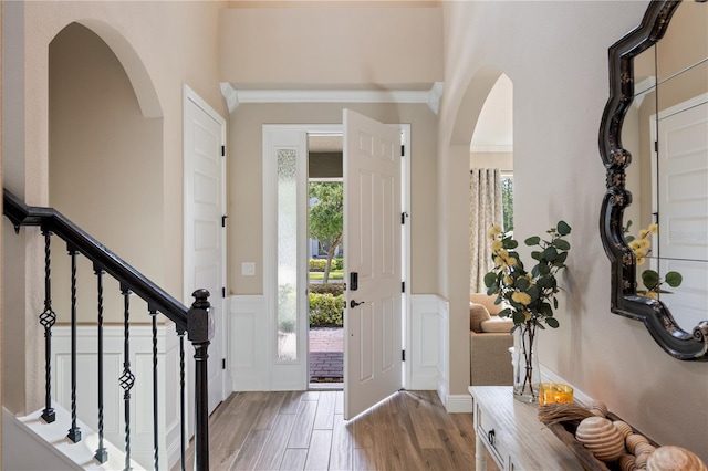 10180 Merrymeeting Bay Dr, Winter Garden, FL 34787 - entrance foyer featuring wainscoting, a decorative wall, arched walkways, wood finished floors, and stairway