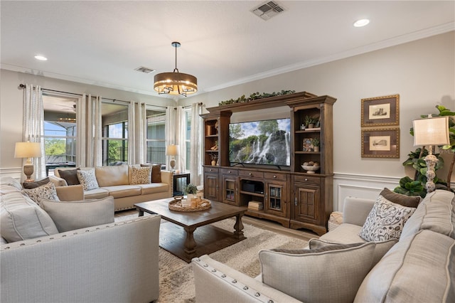 10180 Merrymeeting Bay Dr, Winter Garden, FL 34787 - living room featuring ornamental molding, light wood-type flooring, a chandelier, wainscoting, and a decorative wall