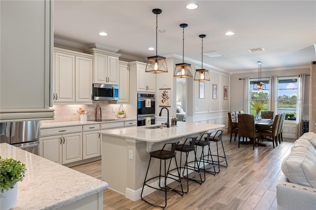 10180 Merrymeeting Bay Dr, Winter Garden, FL 34787 - kitchen with stainless steel appliances, a kitchen breakfast bar, light wood finished floors, open floor plan, and backsplash