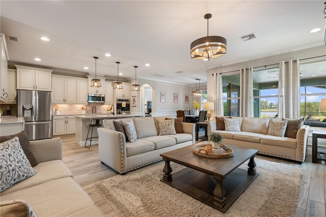 10180 Merrymeeting Bay Dr, Winter Garden, FL 34787 - living area with arched walkways, a chandelier, recessed lighting, crown molding, and light wood-type flooring