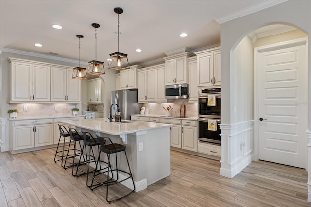 10180 Merrymeeting Bay Dr, Winter Garden, FL 34787 - kitchen with appliances with stainless steel finishes, arched walkways, a breakfast bar area, light wood-type flooring, and crown molding