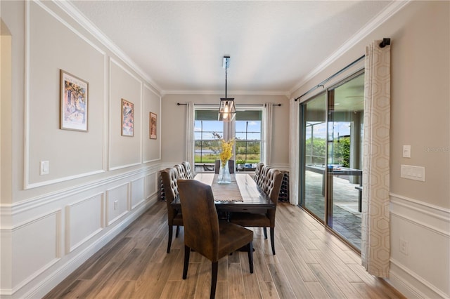 10180 Merrymeeting Bay Dr, Winter Garden, FL 34787 - dining room featuring a decorative wall, ornamental molding, light wood-style flooring, and a wainscoted wall